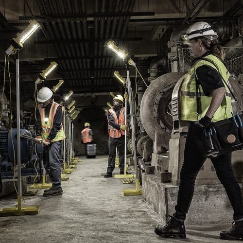 Peli portable lighting systems used by workers in a factory.